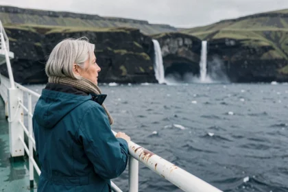 Passagère d'une croisière admirant les falaises volcaniques islandaises depuis le pont d'un navire d'expédition